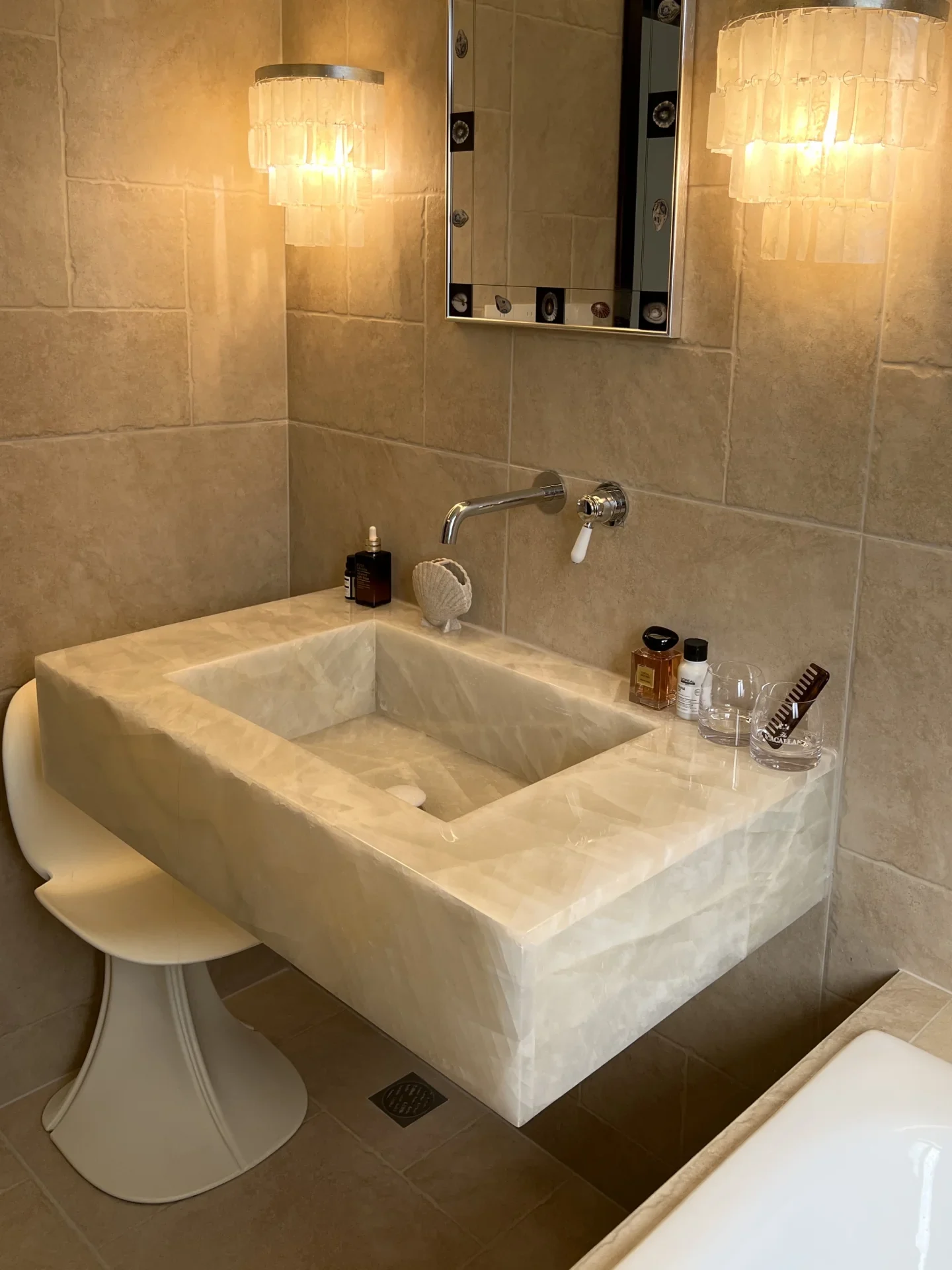 A warm-toned sculptural stone washbasin with wall-mounted fittings