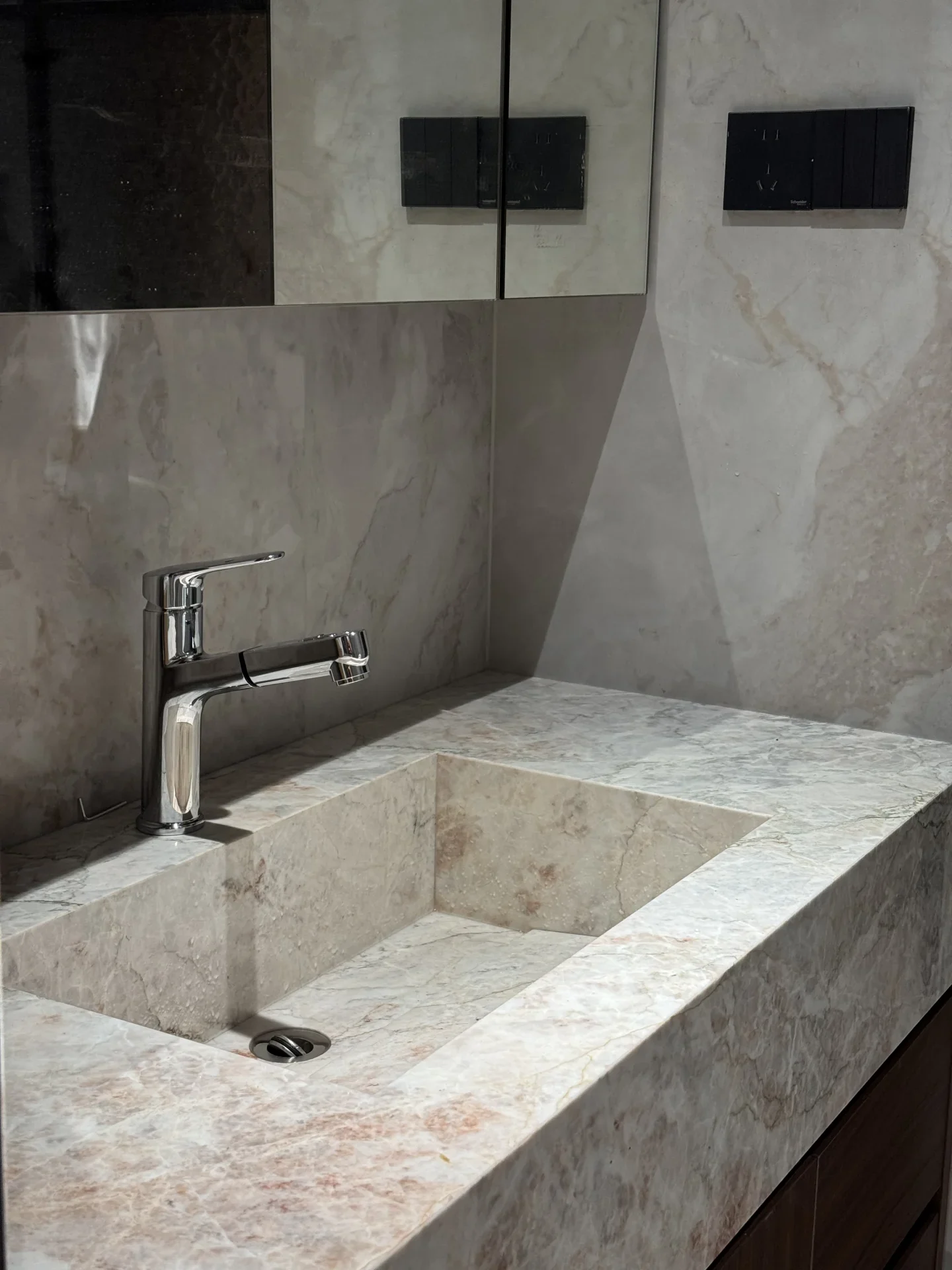 A rectangular stone basin with chrome tapware in a contemporary bathroom
