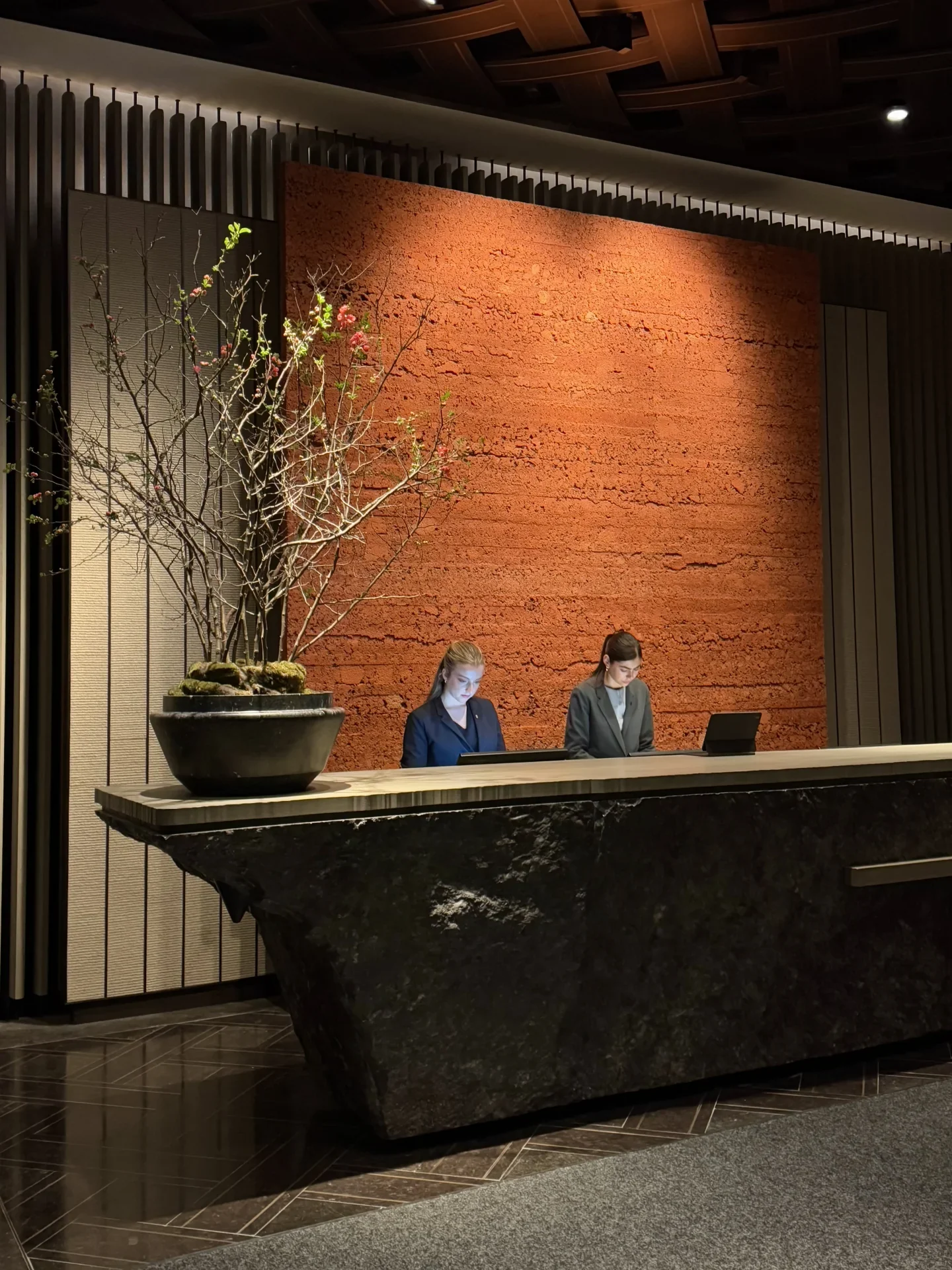 A dark stone reception counter in a warmly lit hotel interior