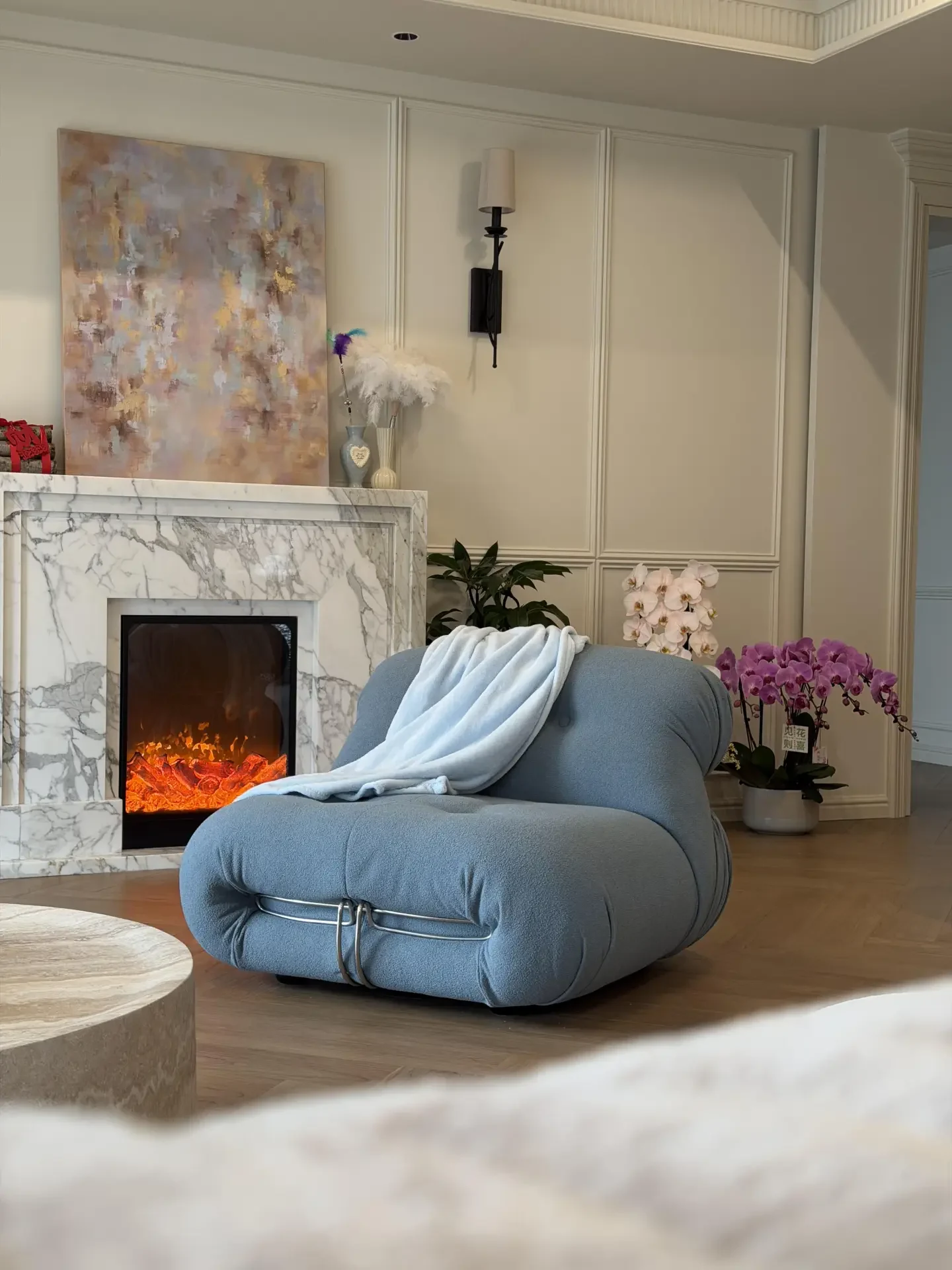 A veined pale stone fireplace in a softly furnished living room