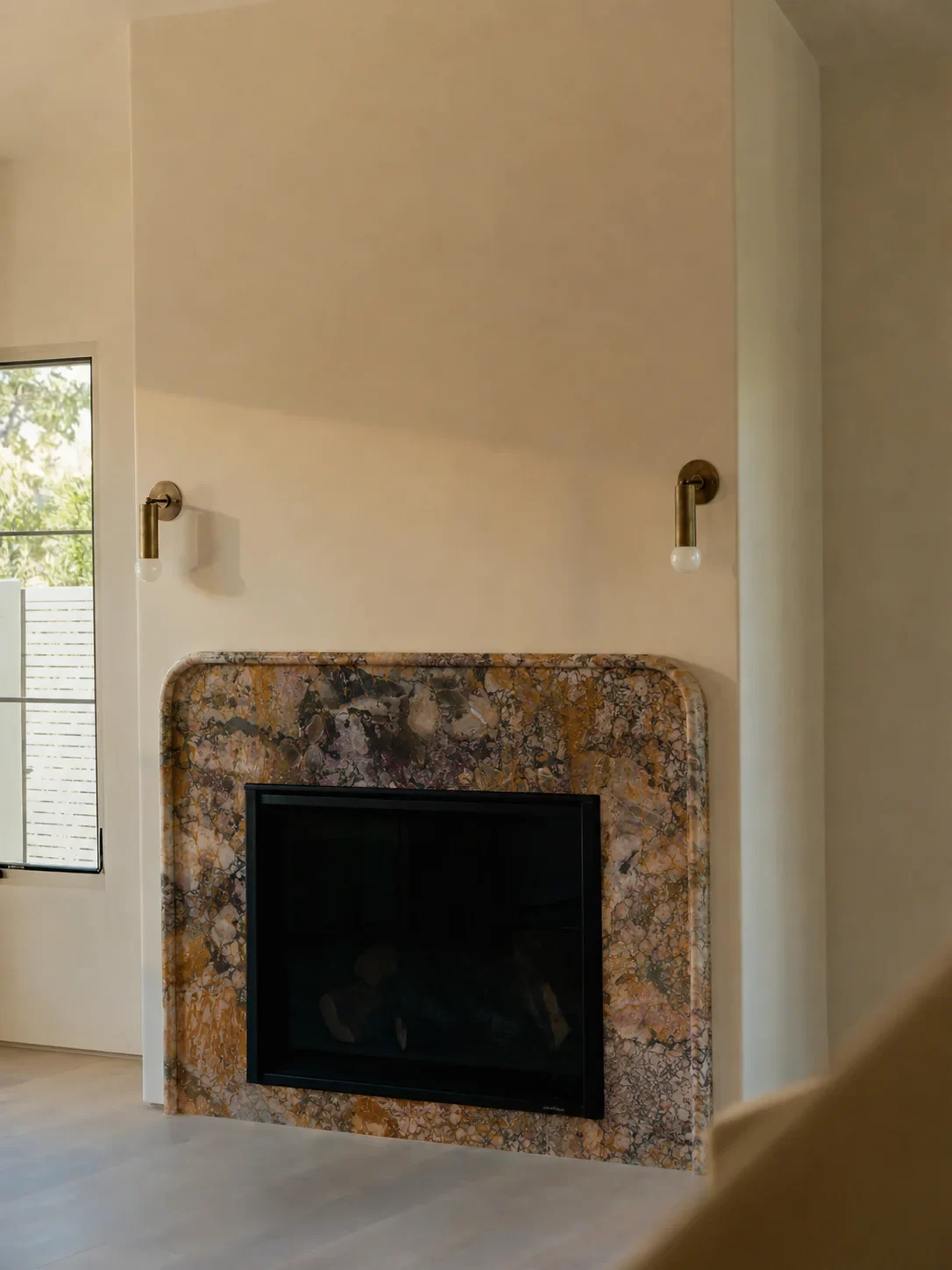 A richly patterned stone fireplace surround in a warm minimalist room