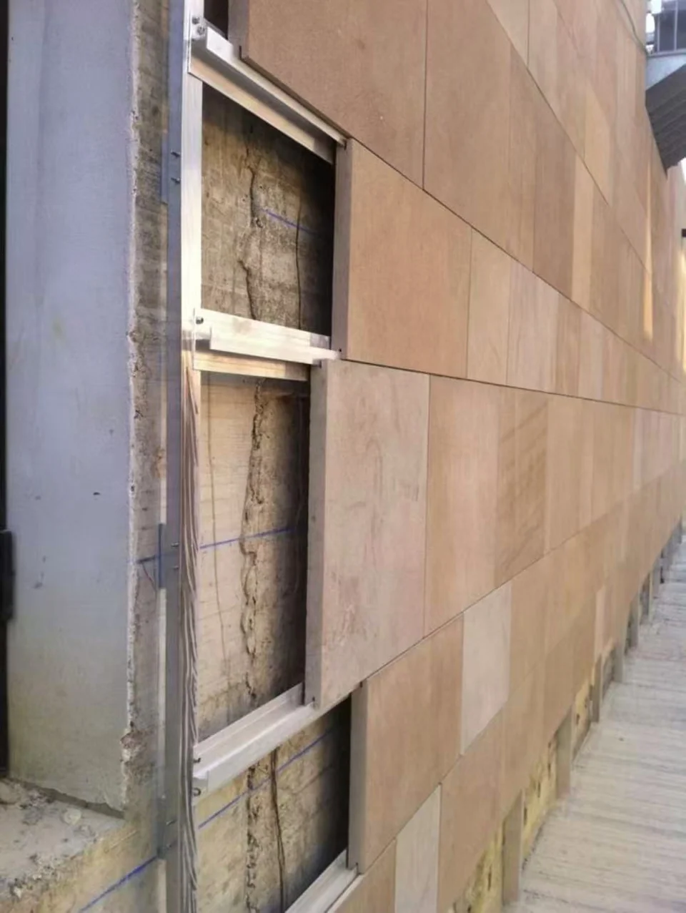Stone wall cladding with its support rail visible at an unfinished edge