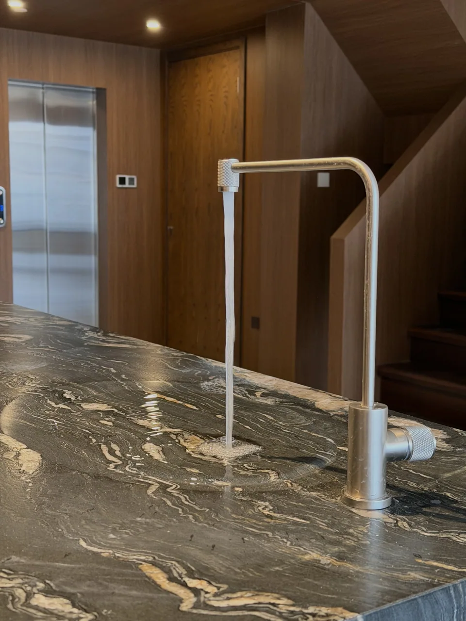 Water flowing toward a discreet sink in a veined stone surface