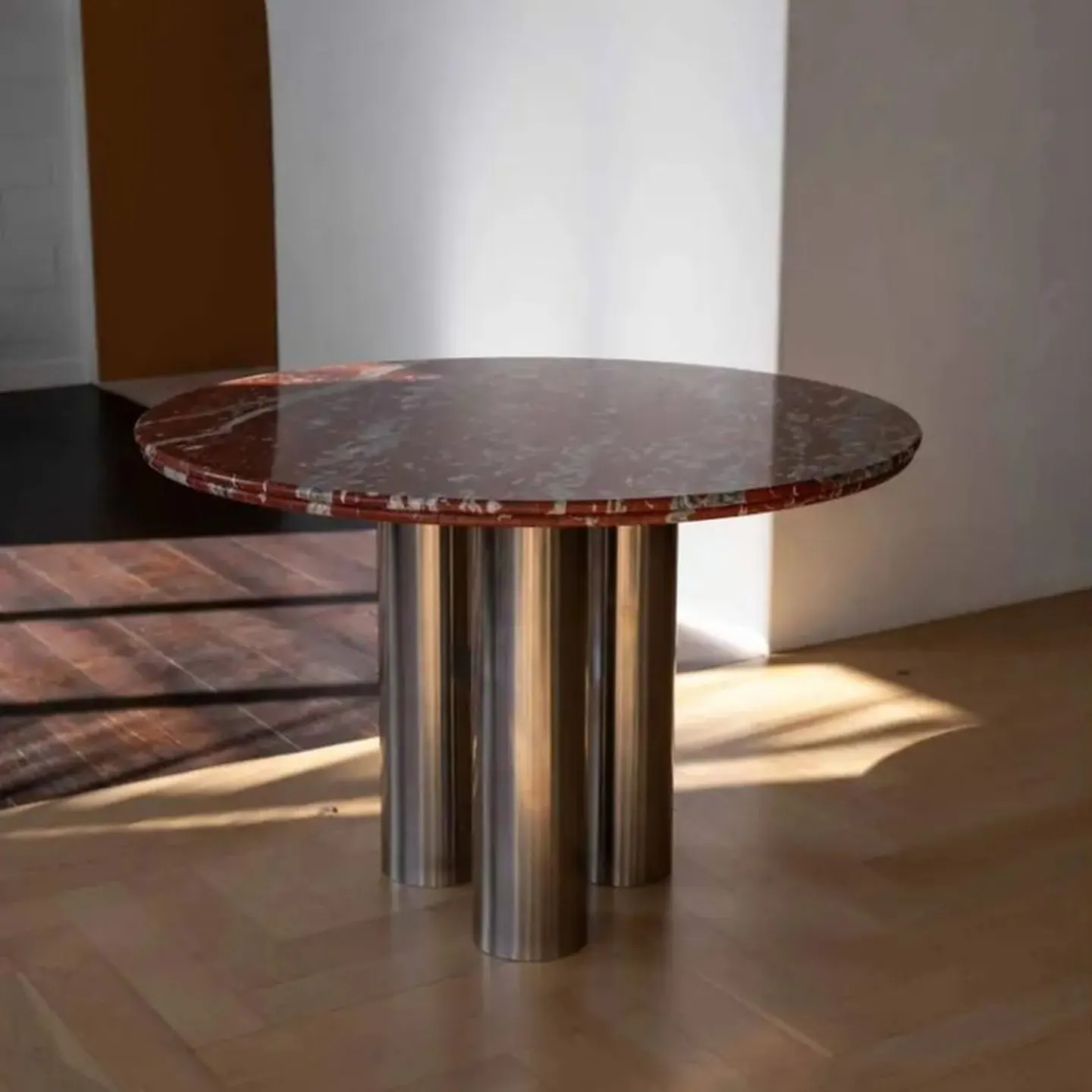Round red marble table on polished steel cylinders