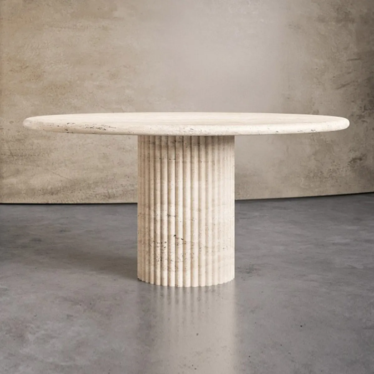 Round travertine table on a fluted drum in a bright room